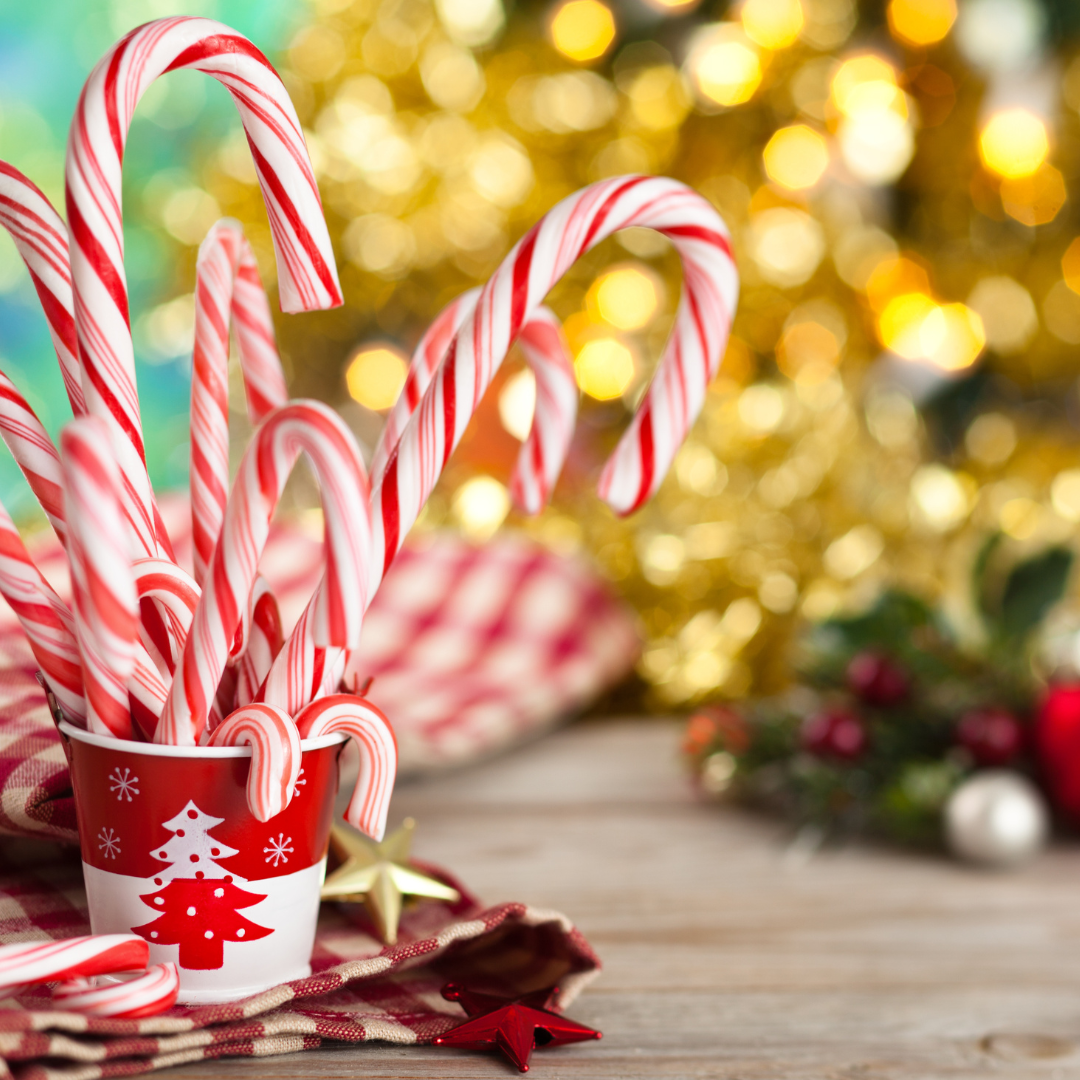 Candy Canes in a red and white christmas tree paper cup with a gold christmas tree in the background
